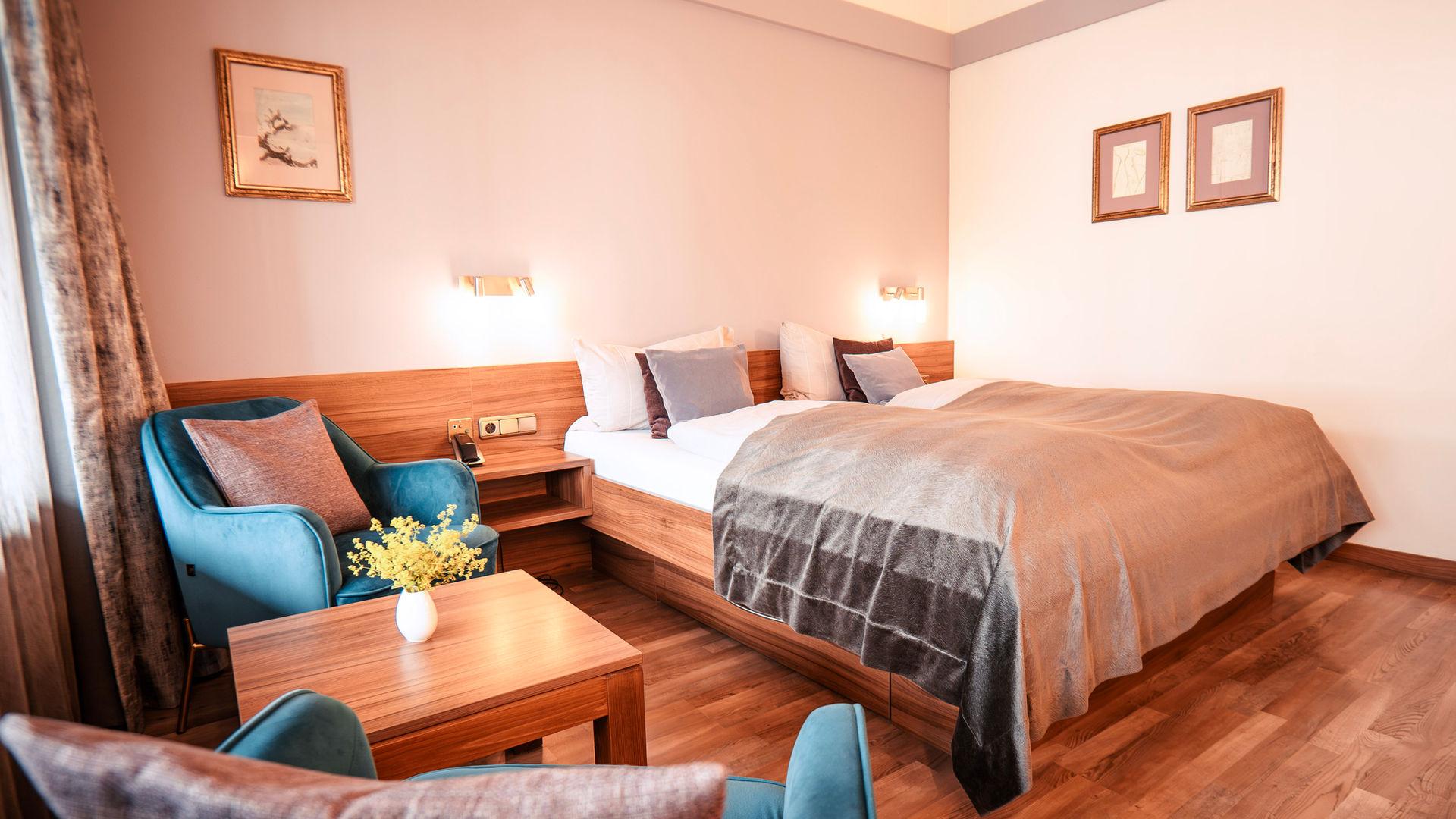 Gemütliches DOPPELZIMMER mit großem Bett, zwei Sesseln und Holzboden.
