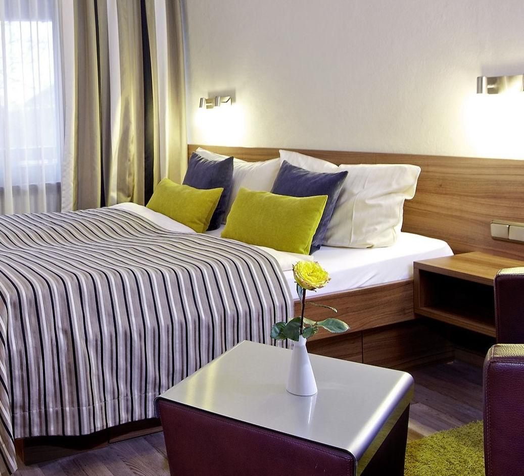 Gemütliches Hotel-Doppelzimmer mit gestreifter Bettwäsche und gelben Kissen.