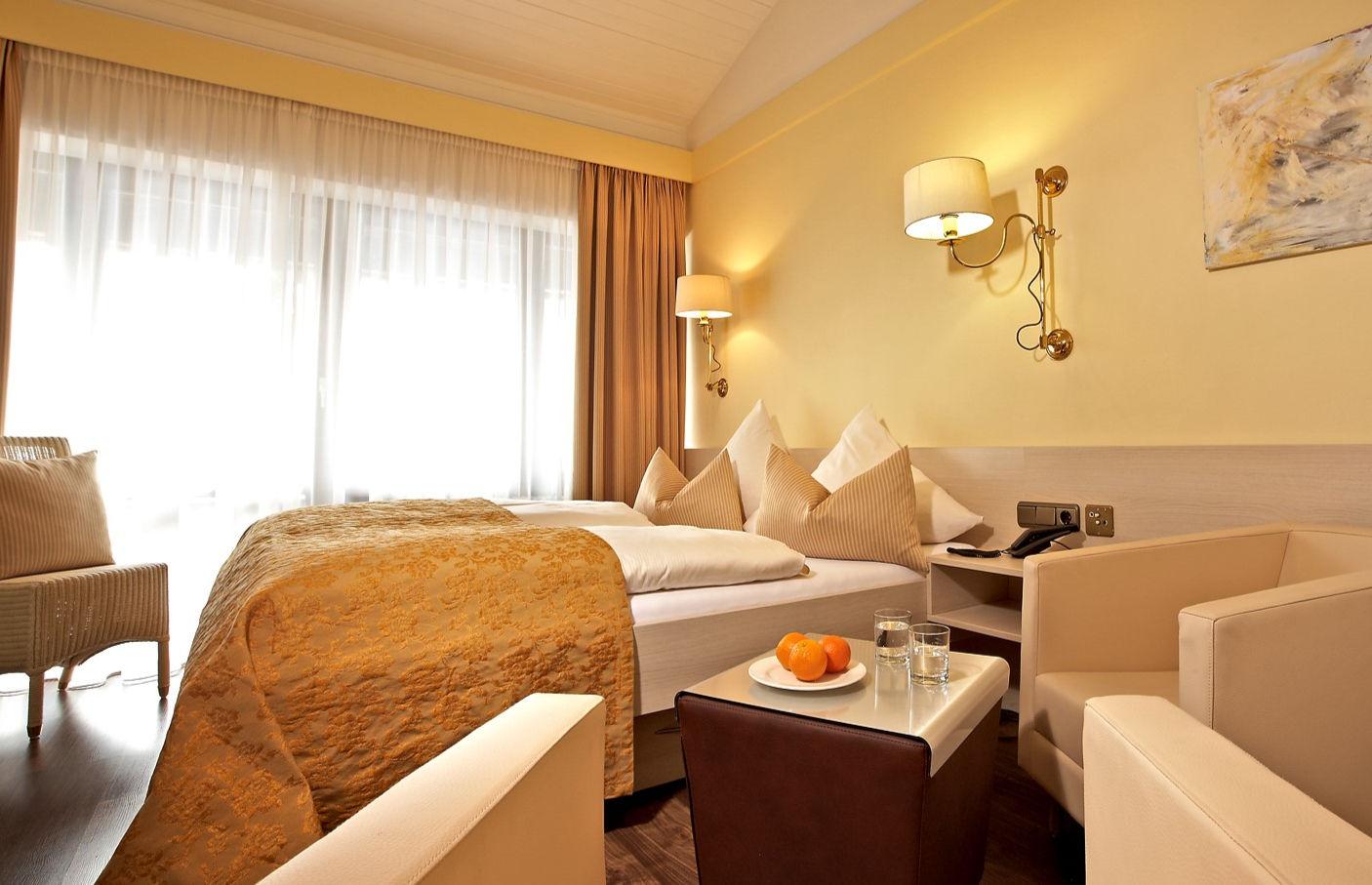 Gemütliches Hotelzimmer mit Doppelbett, Sitzbereich und warmer Beleuchtung.