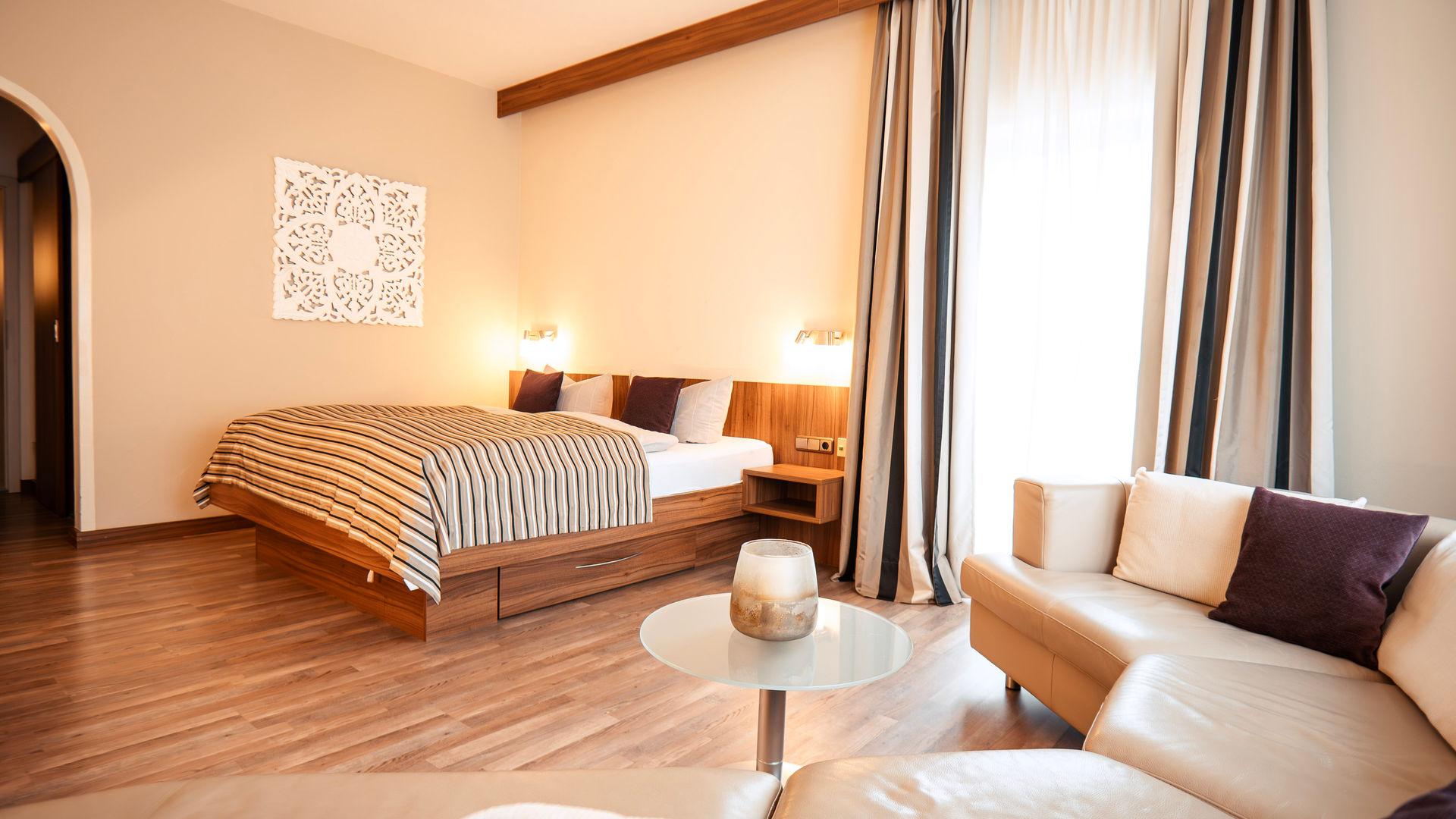 Modern double room with a large bed and a comfortable seating area.