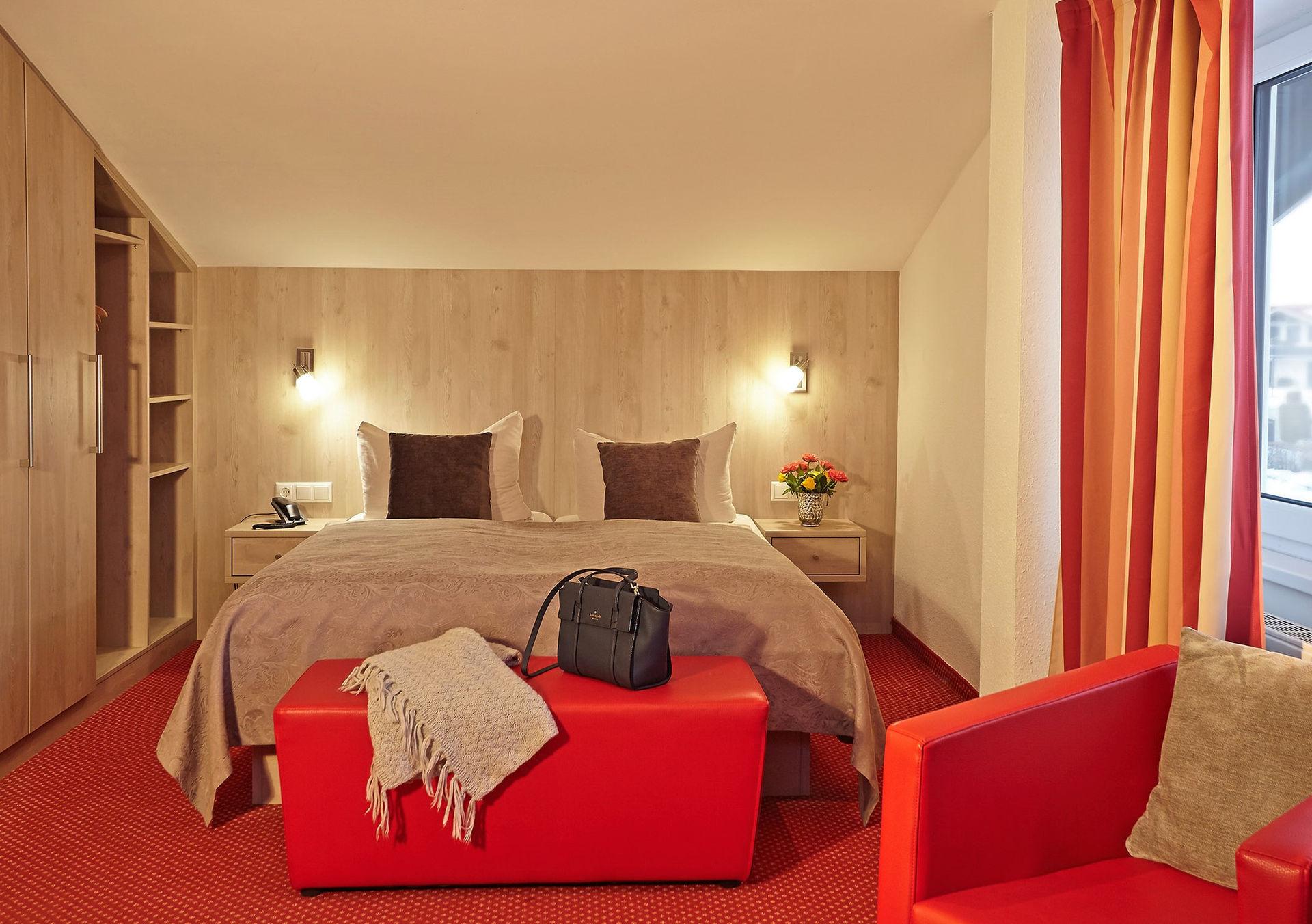 Modernes Hotelzimmer mit Doppelbett, rotem Teppich und Holzverkleidung.