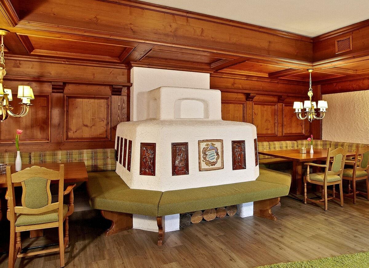 Allgäu parlour with a white tiled stove and wood panelling.