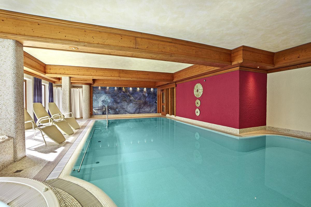 Blick ins Hallenbad mit Liegen an der Fensterfront.
