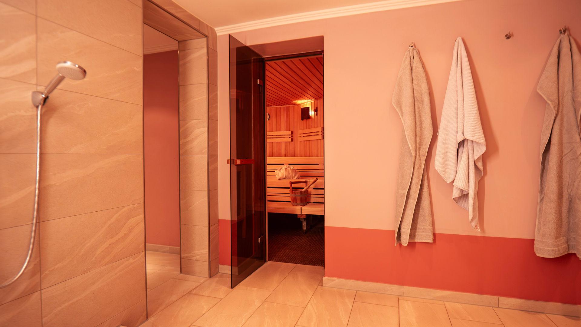 Shower with towels laid out beside the sauna door.