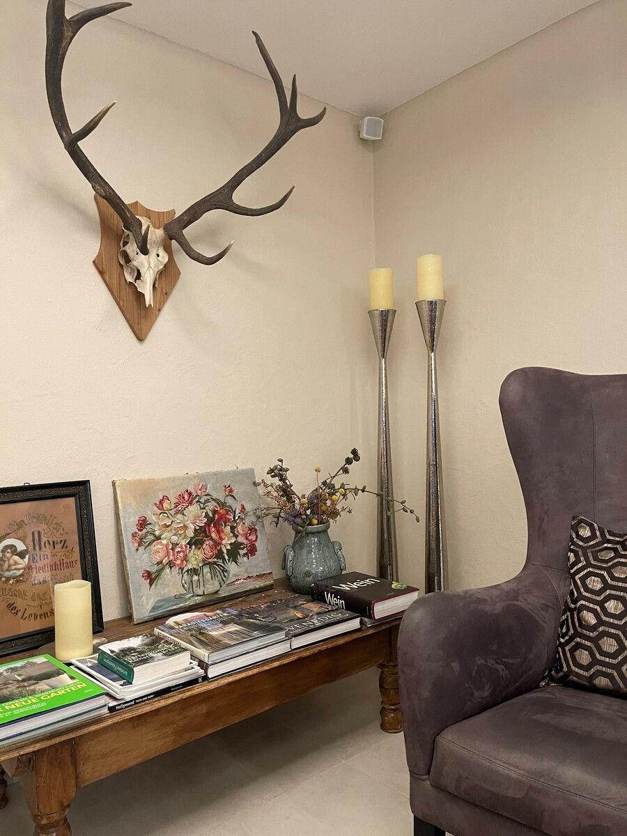 Cosy seating corner with a wing chair, antlers and candles.
