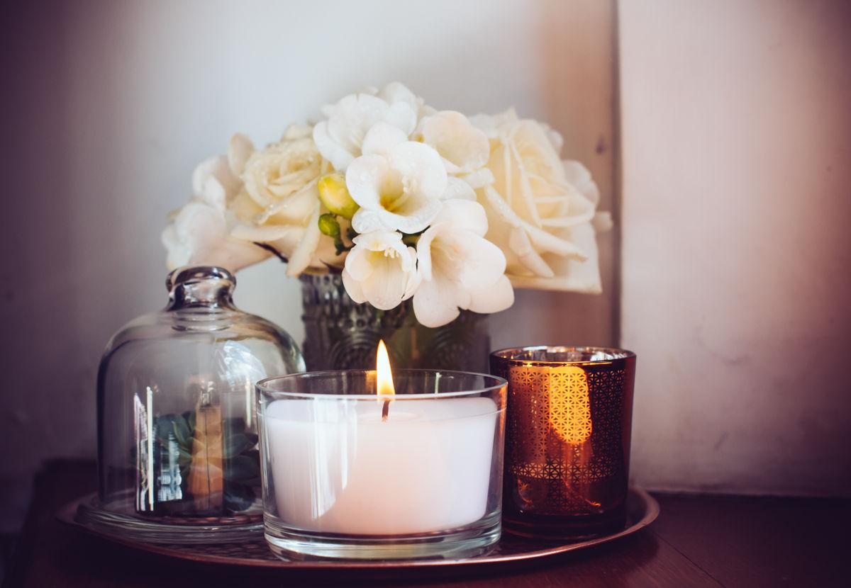 Candle under a glass cloche beside white flowers.