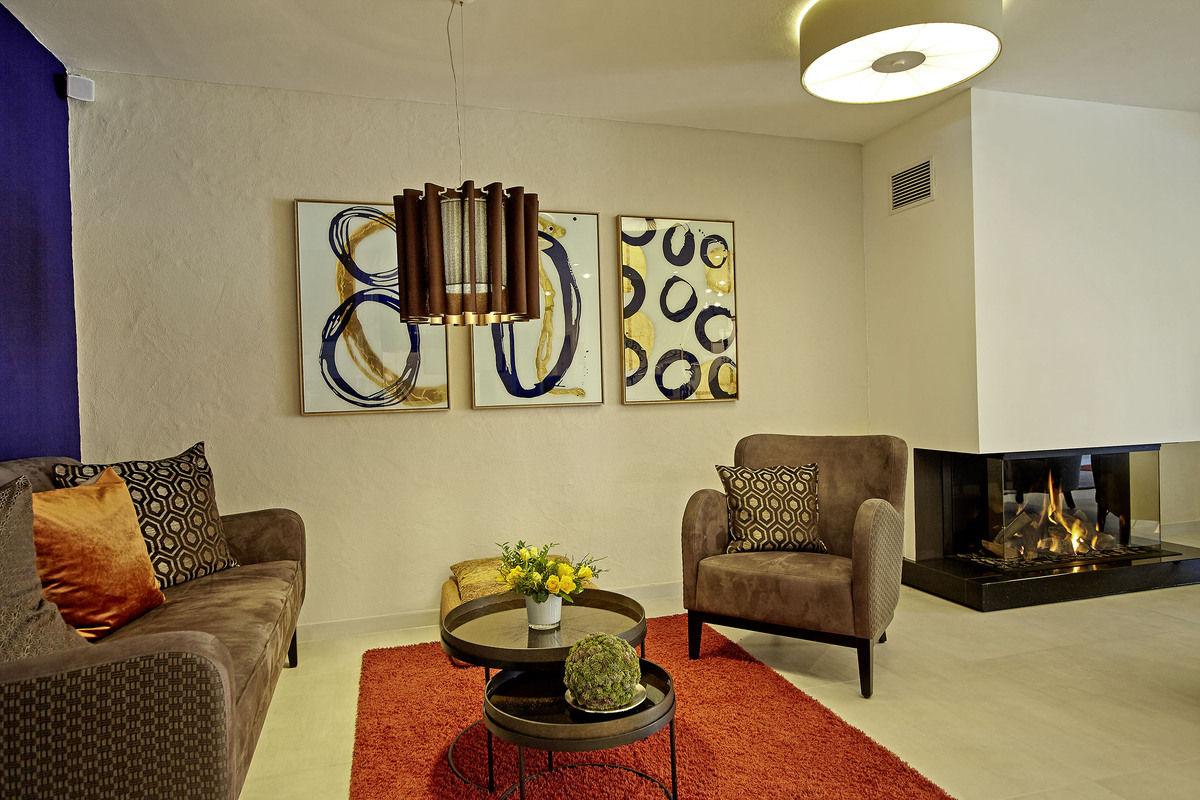 Lounge with fireplace, armchairs and abstract art on the wall.