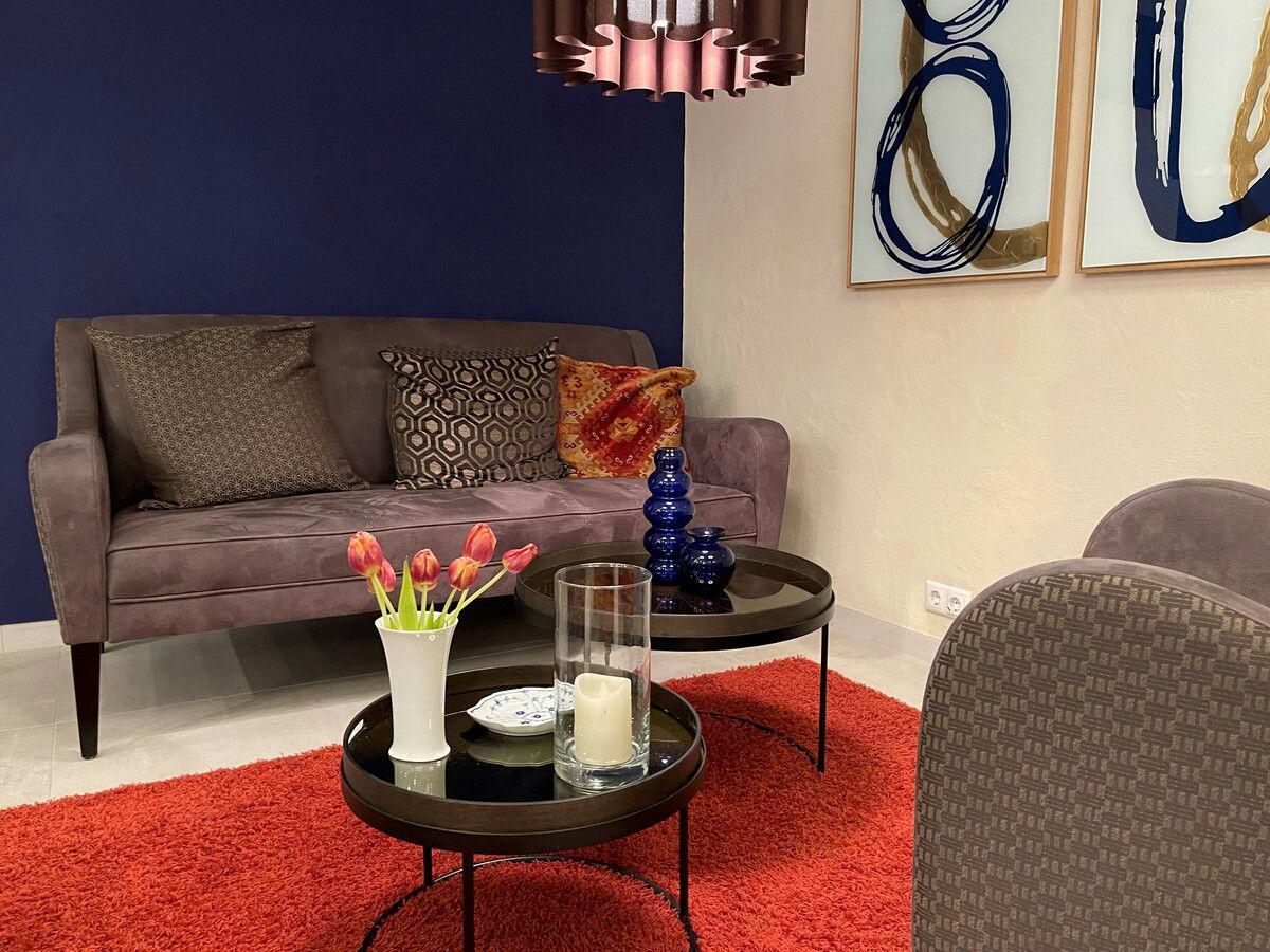 Lounge area with sofa, red carpet and tulips on the side table.