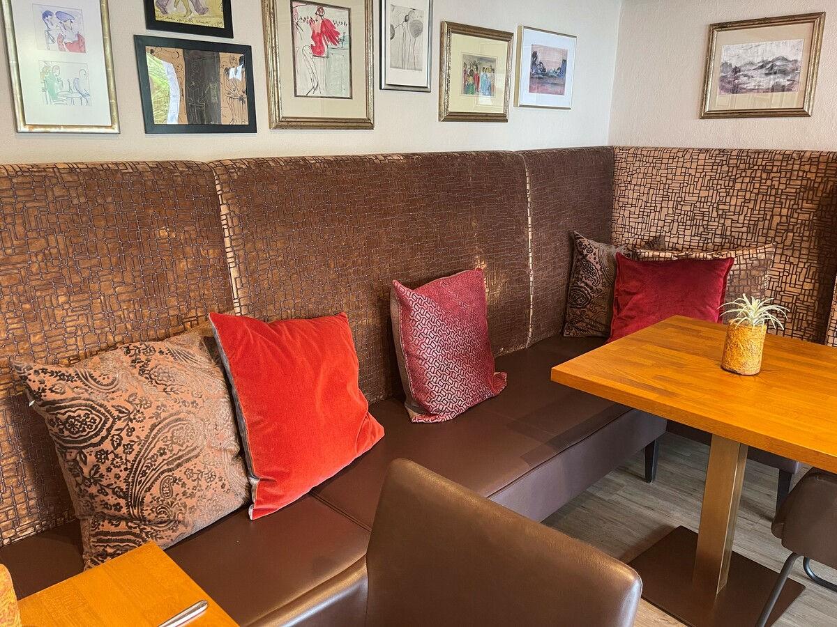 Restaurant niche with an upholstered bench, cushions and a picture gallery.