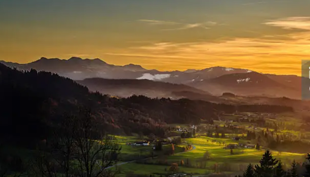 Goldener Sonnenuntergang über Bergen, Wald und Tälern im Allgäu.
