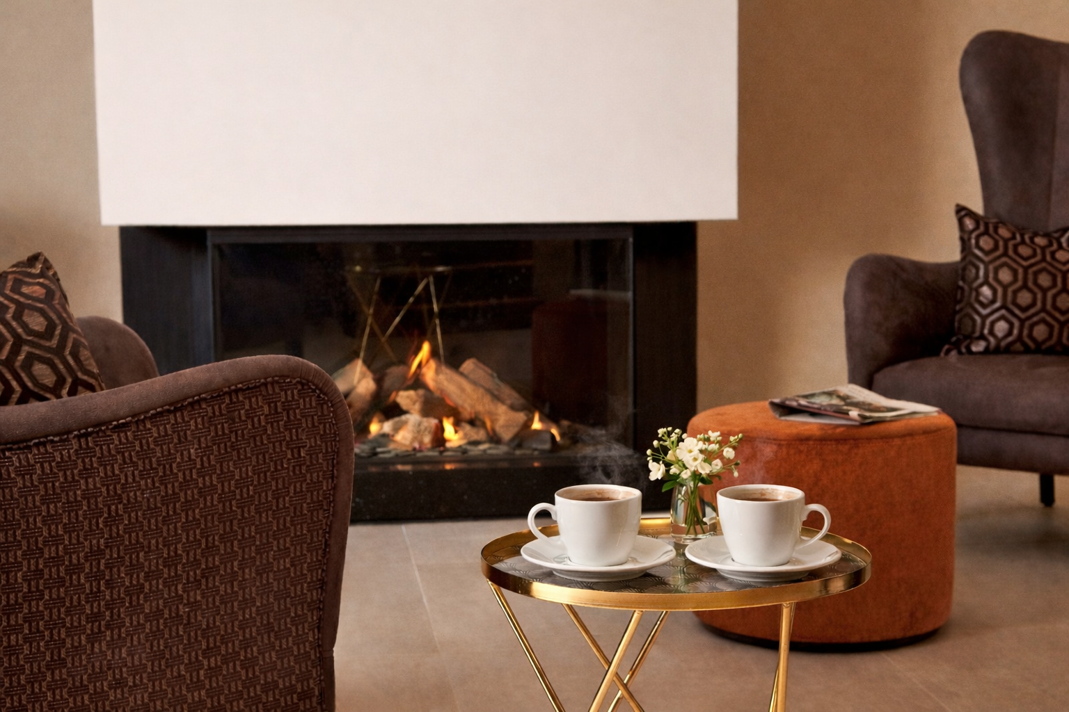 Gemütlicher Sitzbereich am Kamin mit zwei dampfenden Tassen Kaffee.