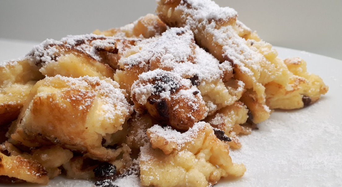 Goldbrauner Kaiserschmarrn, bestreut mit feinem Puderzucker und Rosinen.