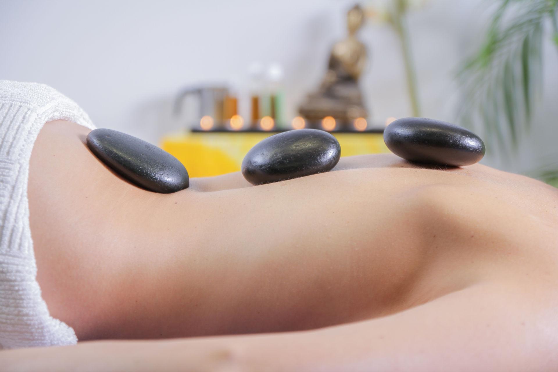 Hot-Stone-Massage mit warmen Steinen auf dem Rücken.
