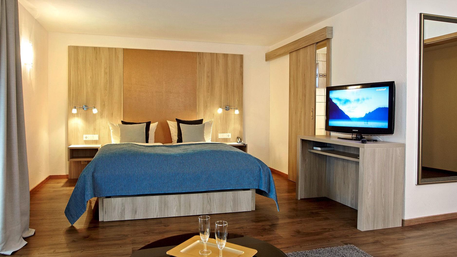 Hotelzimmer mit Doppelbett und bereitstehenden Sektgläsern zur Begrüßung.