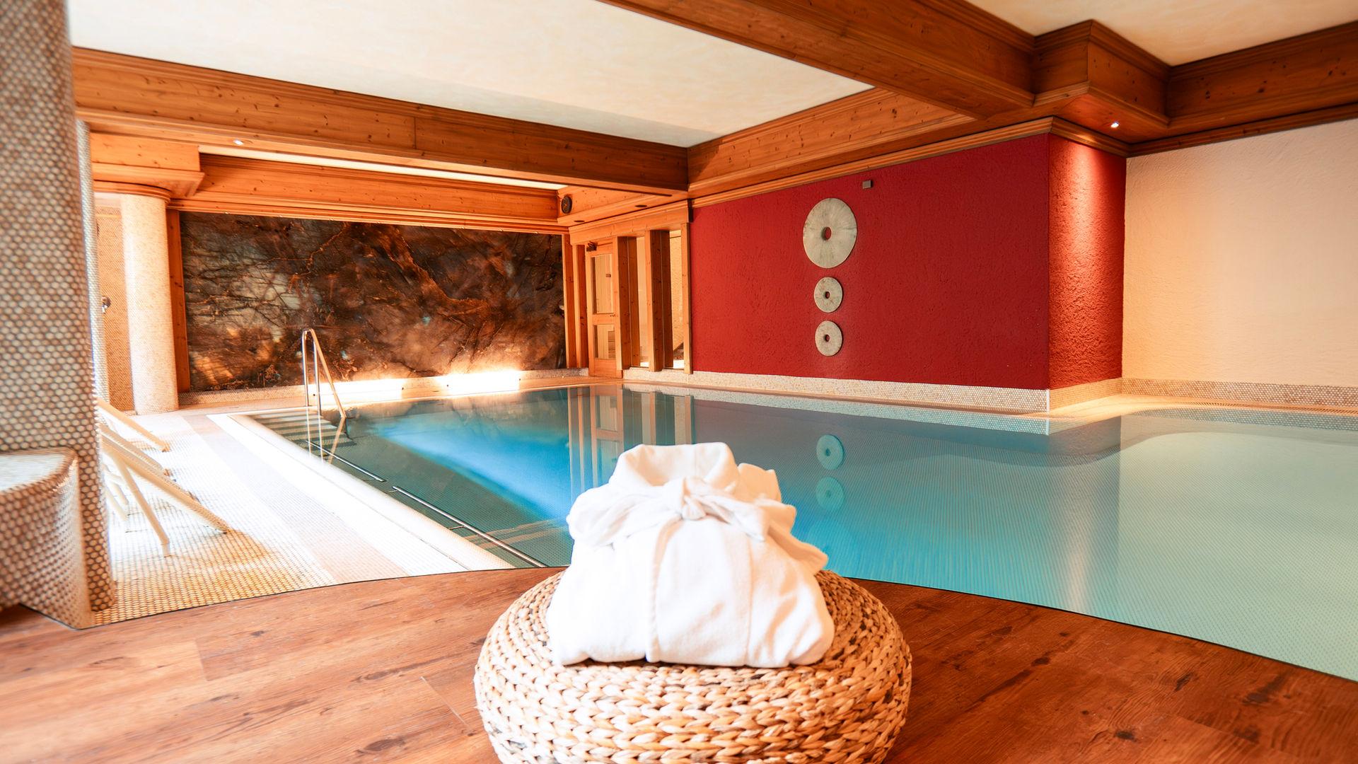Hallenbad des Hotel Bavaria mit Bademantel an blauer Wand.